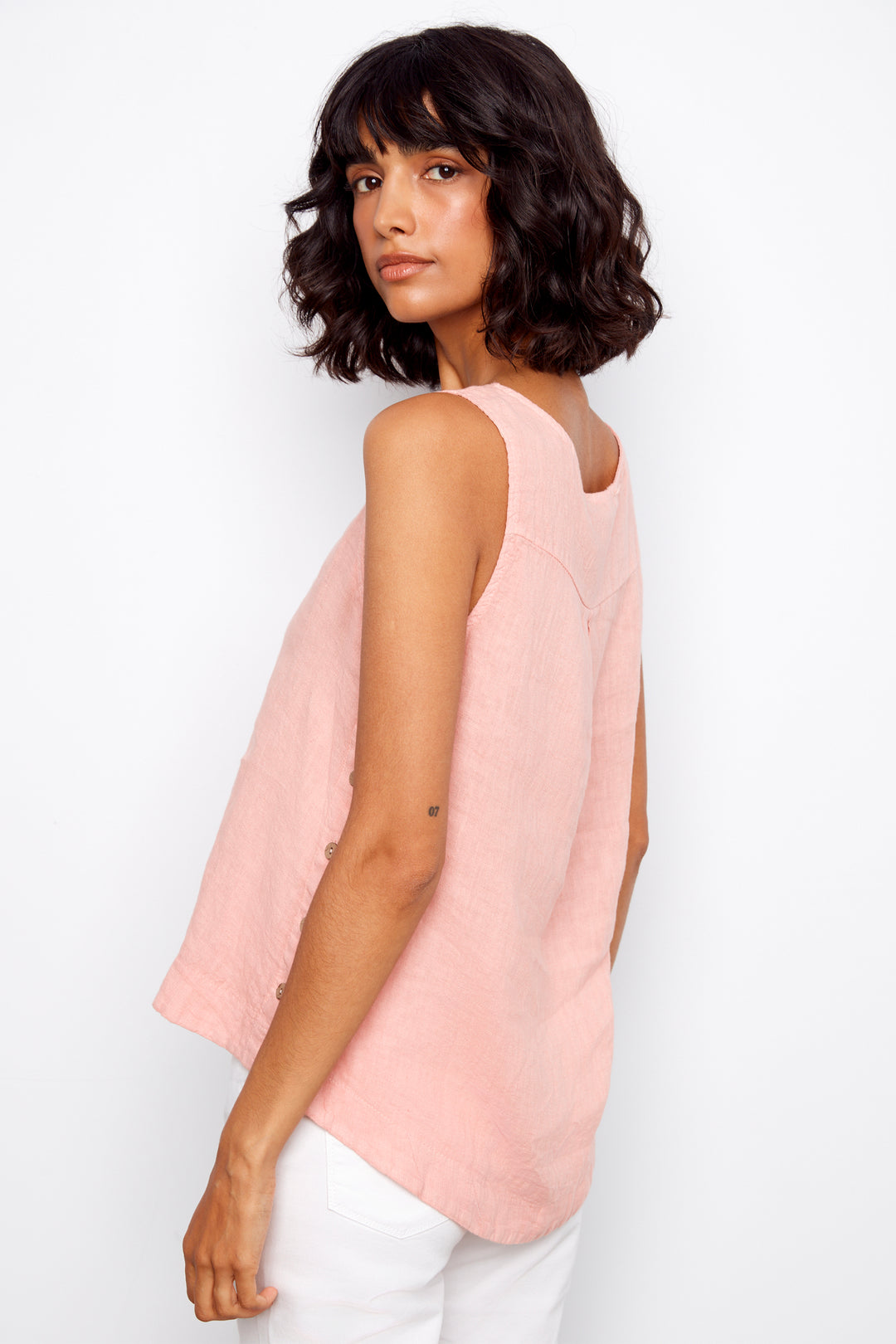 Woman wearing a light pink sleeveless top against a white background