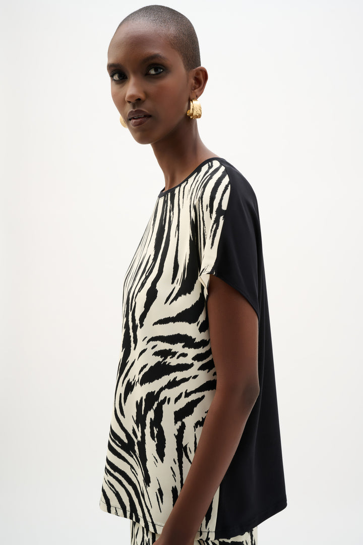 Woman wearing a black and white zebra print dress on a plain background