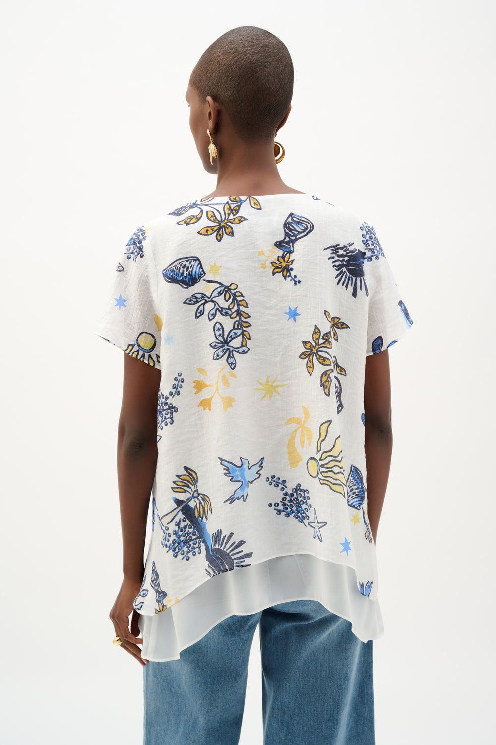 Person wearing a white blouse with colorful floral patterns on a white background