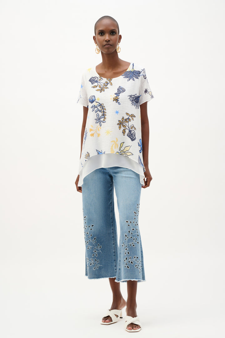 Woman wearing a floral top and light blue pants on a white background