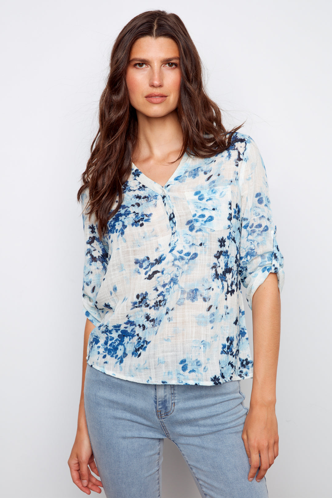 Woman wearing a blue floral blouse and light blue jeans on a white background