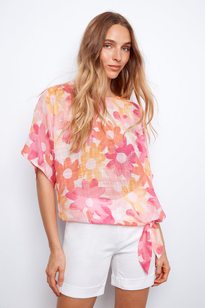 Woman wearing a floral blouse and white shorts on a white background