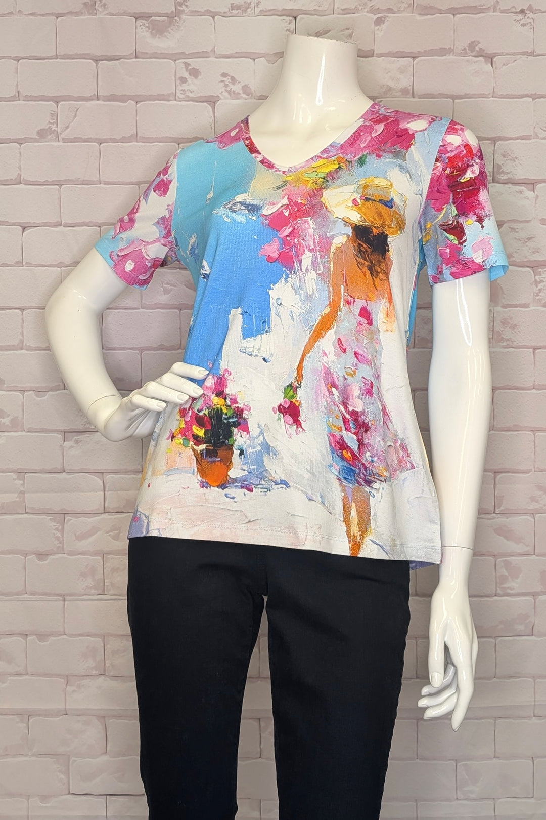 Mannequin wearing a colorful printed top with v-neck and short sleeves with a brick wall background
