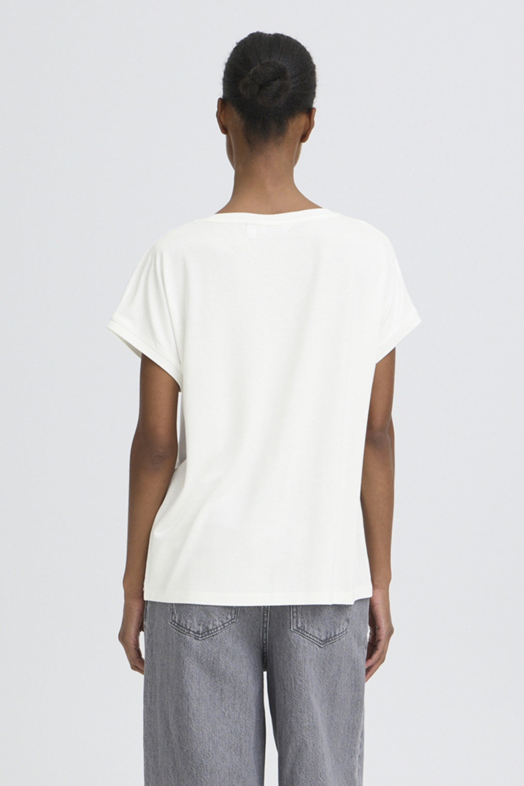 Person wearing a white t-shirt and gray pants on a light gray background