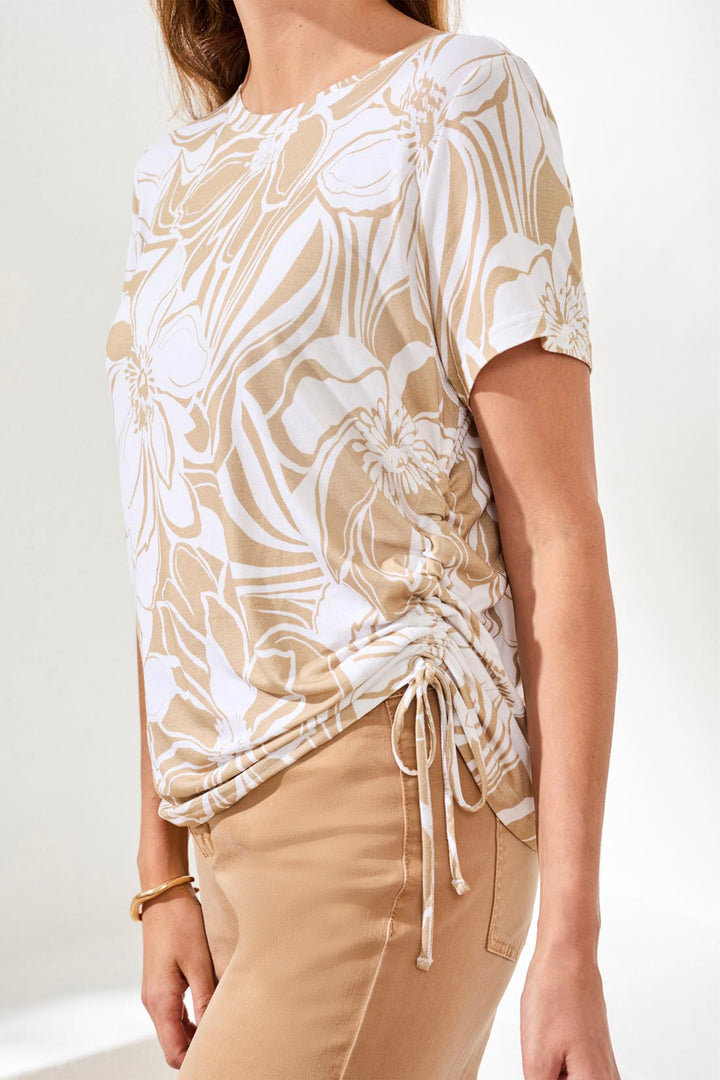 Woman wearing a beige and white patterned top with a plain background