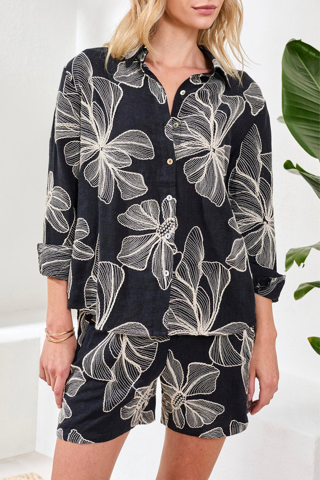 Person wearing a black floral shirt and shorts set with a white background