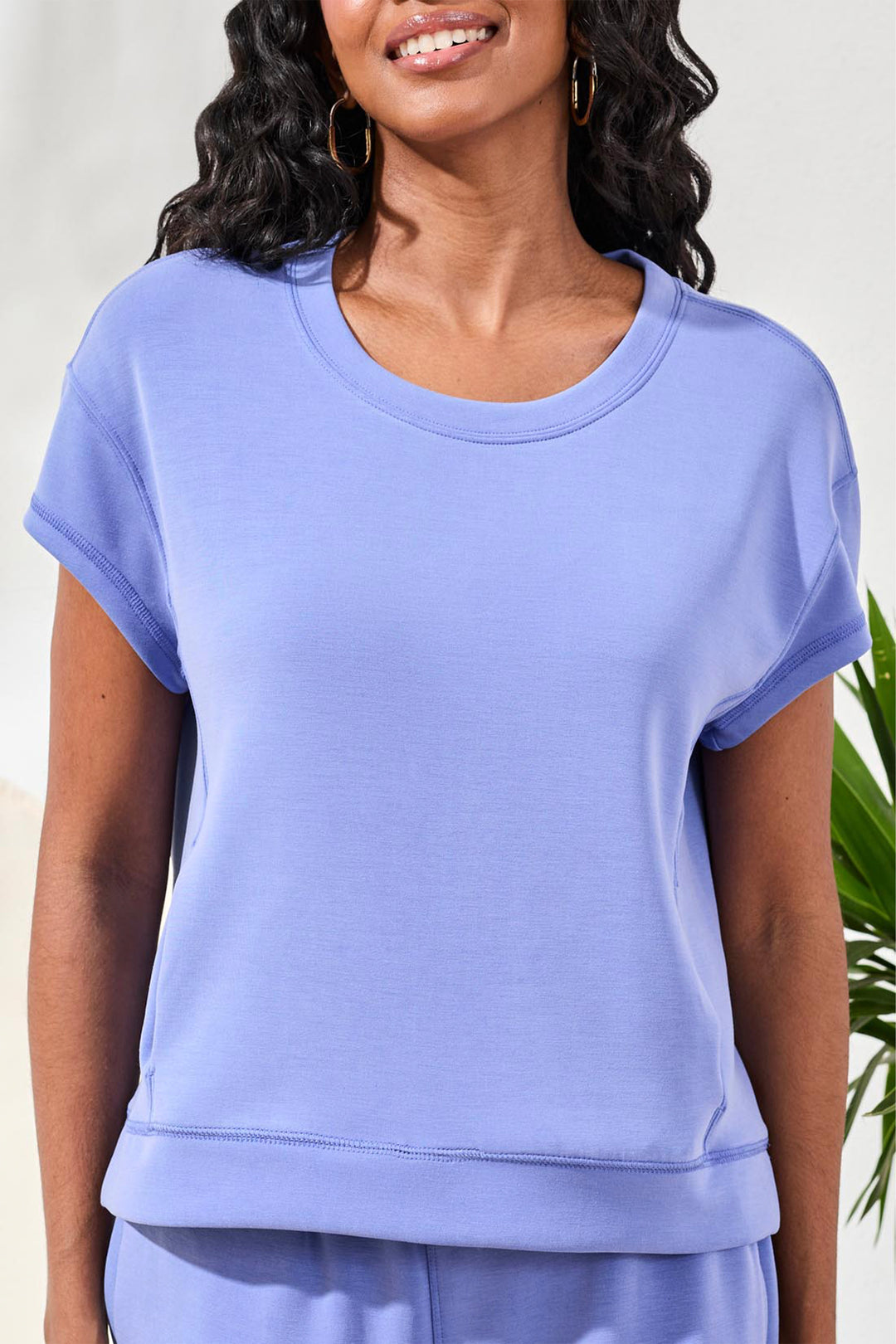 Woman wearing a light top with short cap sleeves with a white background