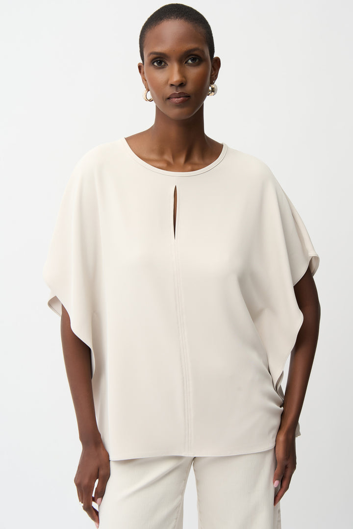 Woman wearing a beige blouse with a cut-out design on a white background