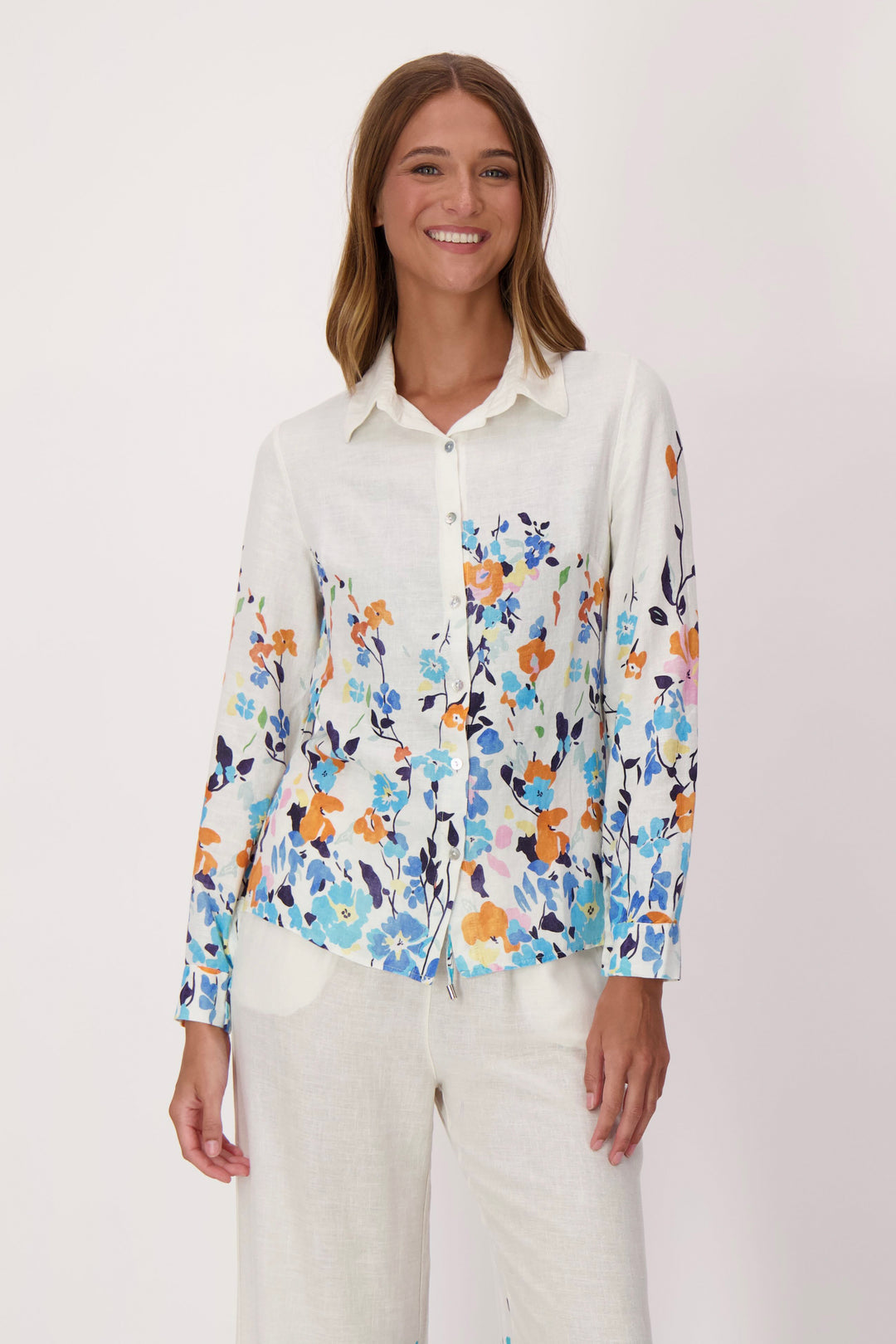 Woman wearing a white light dress shirt with colorful floral pattern on a plain background