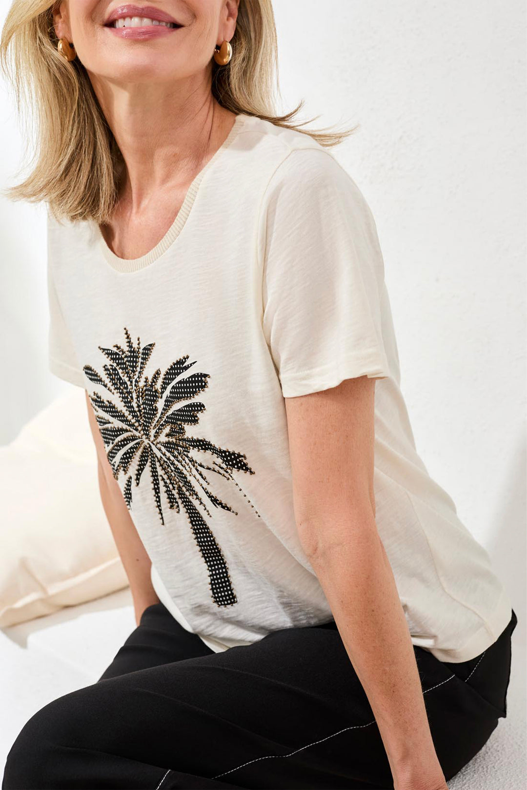Woman wearing a white cotton t-shirt with a black palm tree design on a white background