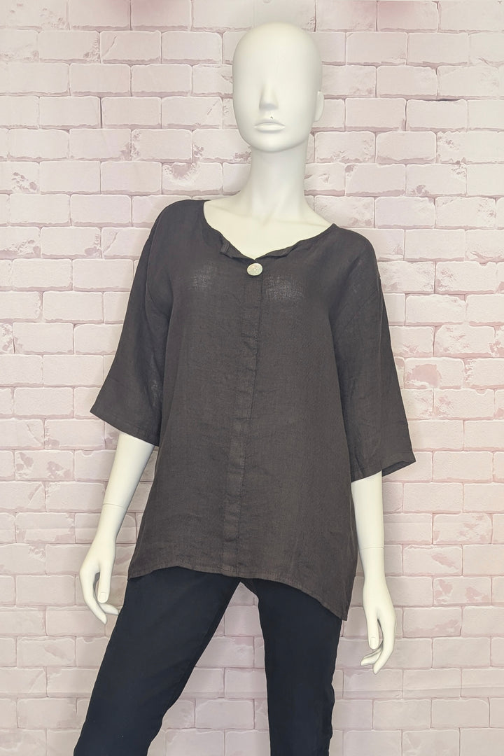 Mannequin wearing a dark gray single button blouse with a brick wall background
