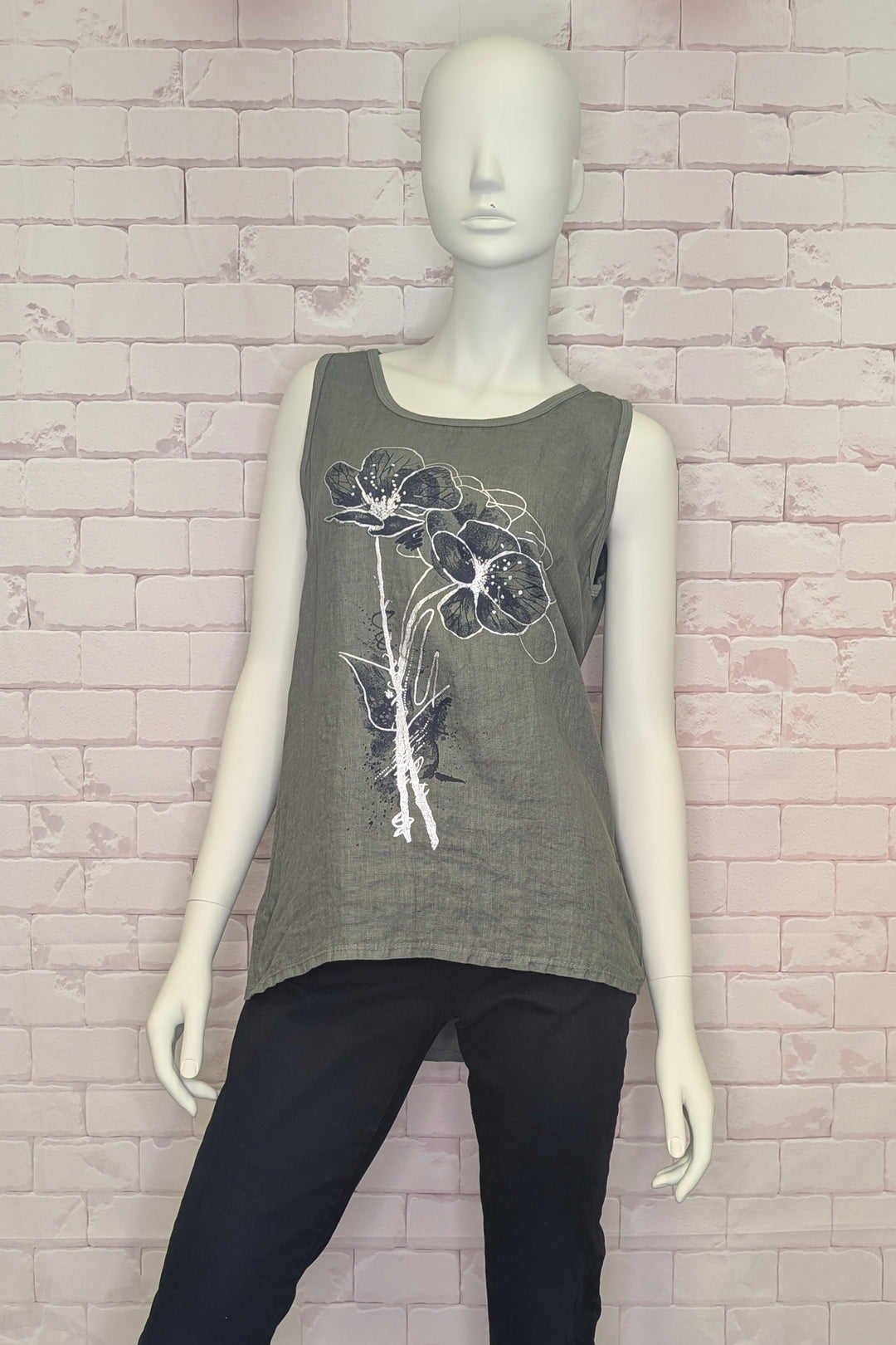 Mannequin wearing a gray tank top with floral design against a brick wall.
