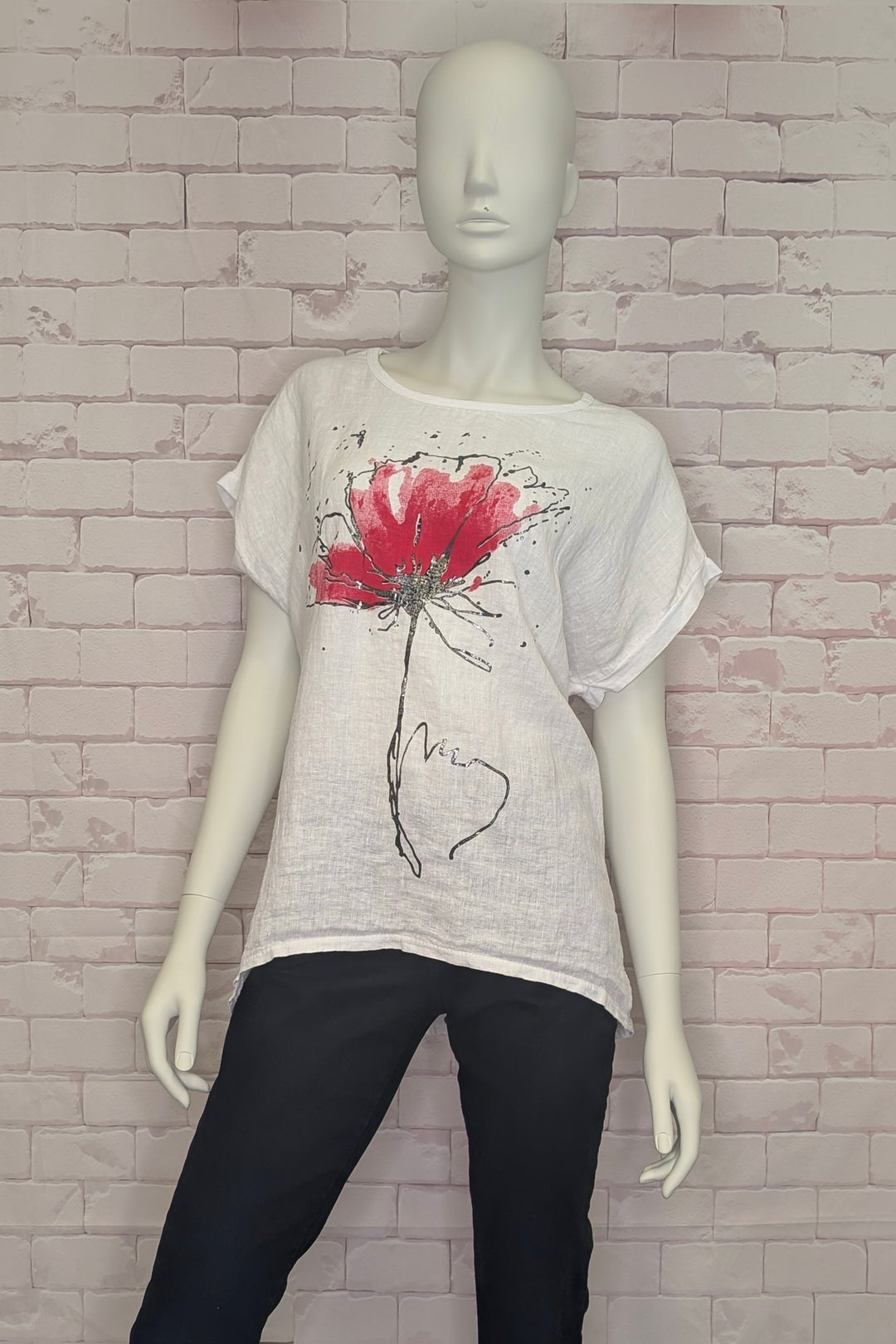 Mannequin wearing a white t-shirt with a red floral motif against a brick wall.