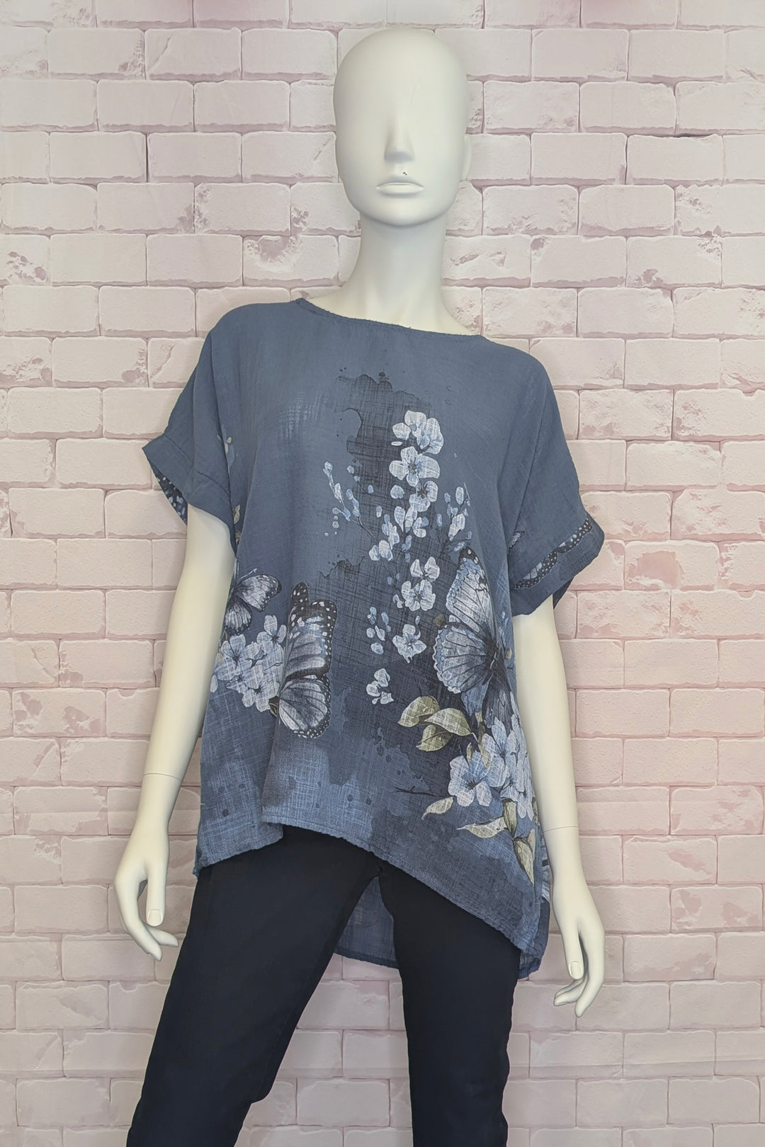 Mannequin wearing a gray floral cotton blouse against a brick wall background