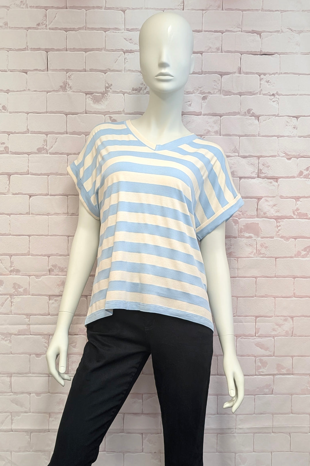 Mannequin wearing a blue and white striped shirt against a brick wall.