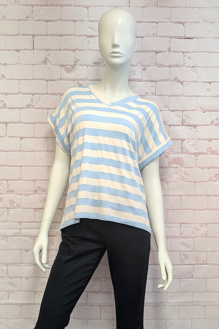 Mannequin wearing a blue and white striped shirt against a brick wall.