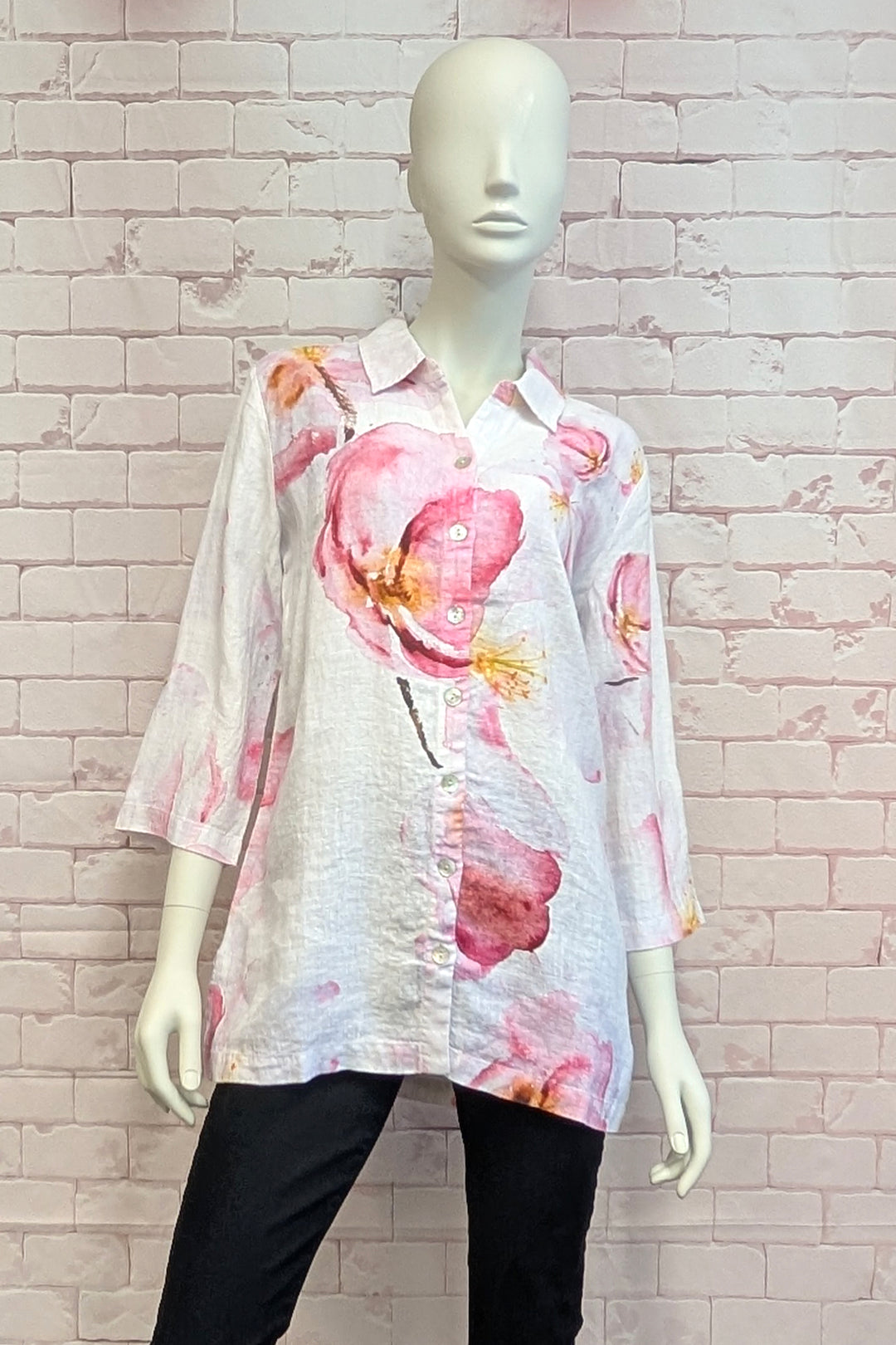 Mannequin wearing a floral big blouse shirt with a white brick wall background