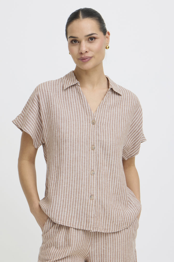 Woman wearing a beige striped short sleeve button shirt and pants on a white background