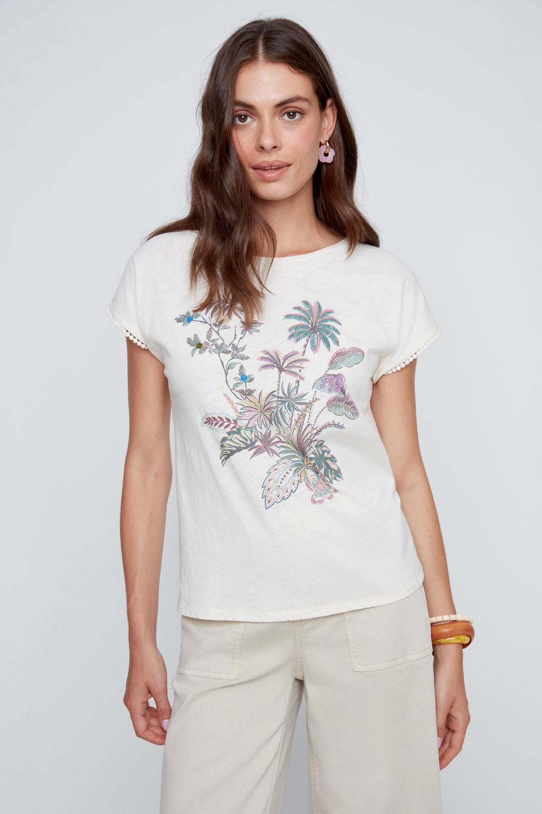 Woman wearing a white cotton crewneck t-shirt with floral design on a plain background