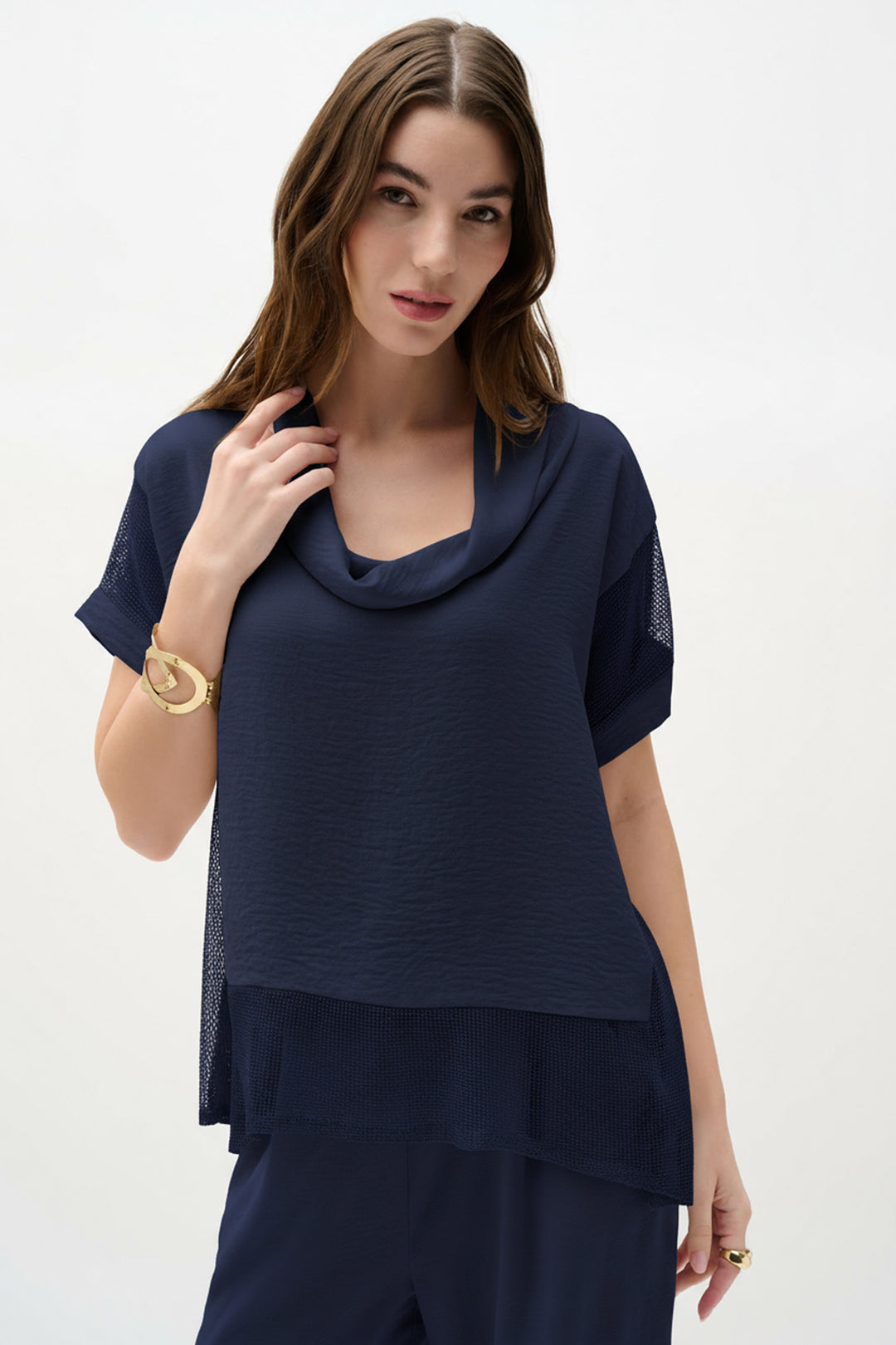 Woman wearing a navy blue outfit with a cowl neck mesh top on a white background