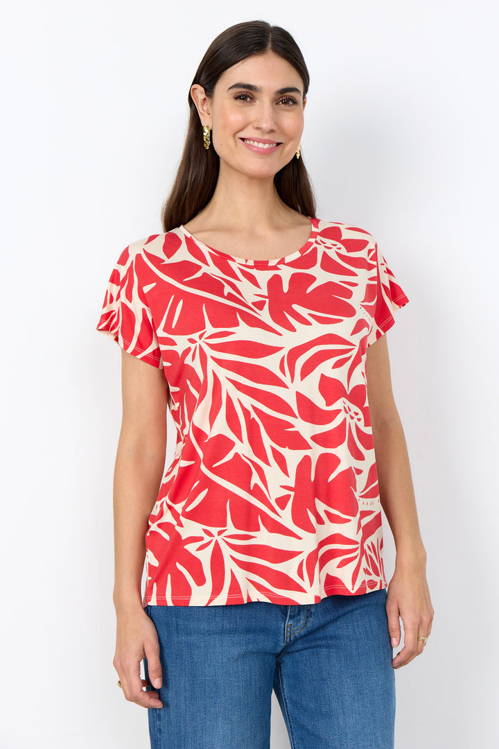 Woman wearing a red and white floral leaves top with blue jeans on a white background