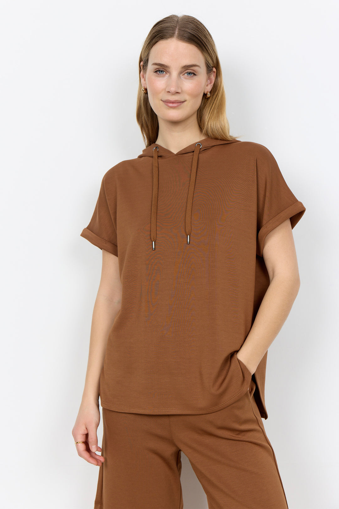 Woman wearing a toffee brown-colored outfit with a plain background