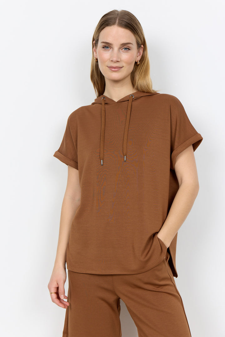 Woman wearing a toffee brown-colored outfit with a plain background