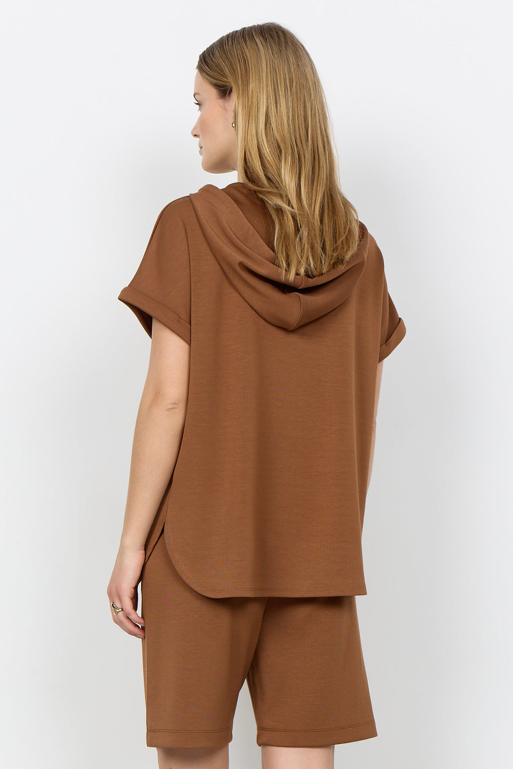 Woman wearing a toffee brown-colored outfit with a plain background