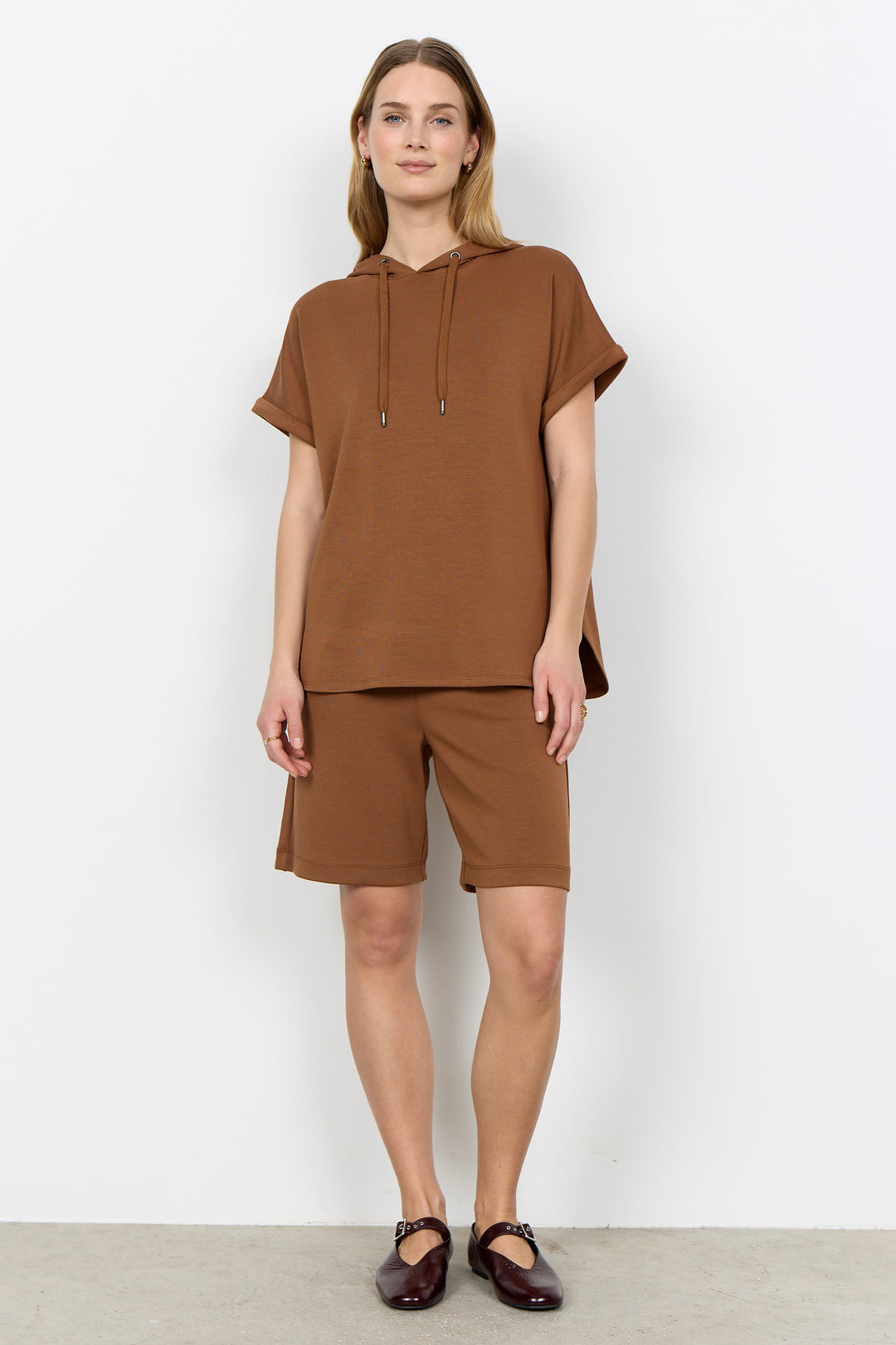 Woman wearing a matching brown outfit on a plain white background