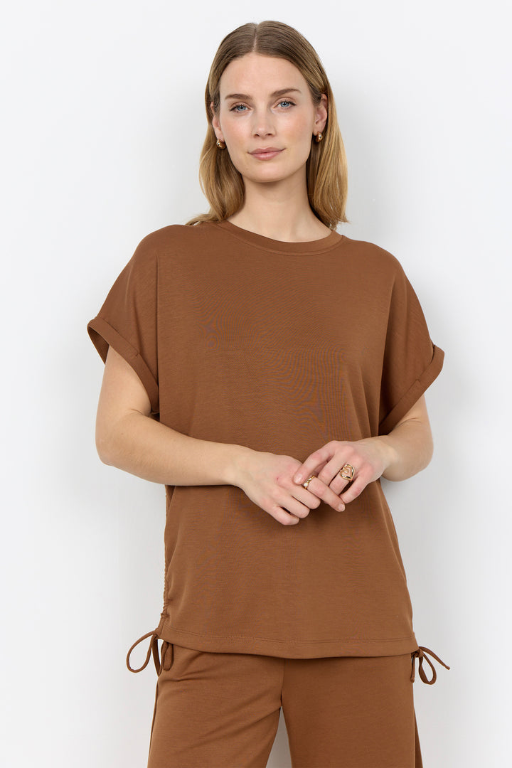 Woman wearing a toffee-colored top and matching shorts against a white background.