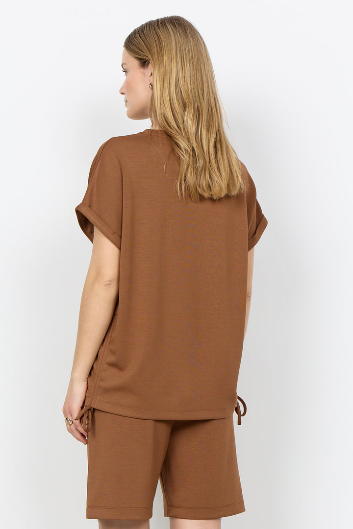 Woman wearing a toffee-colored top and matching shorts against a white background.
