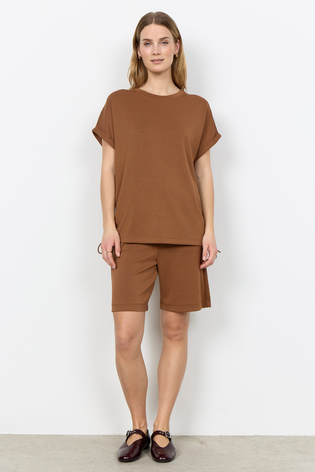 Woman wearing a toffee-colored top and matching shorts against a white background.