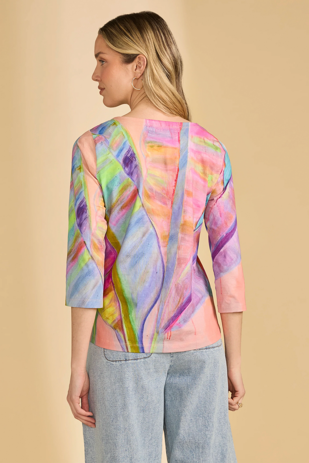 Woman wearing a colorful, patterned top with a beige background