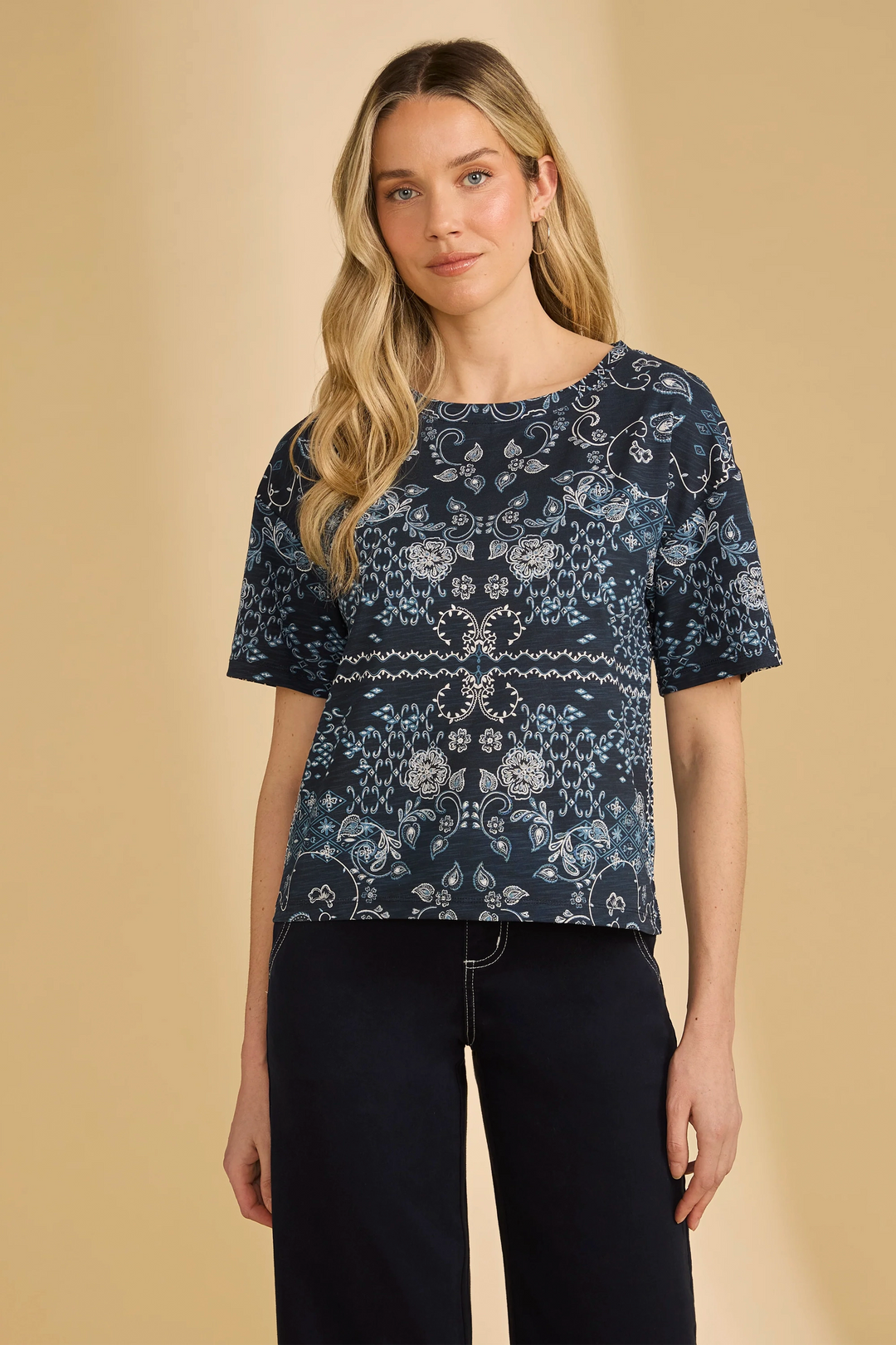 Woman wearing a navy blue patterned top against a beige background