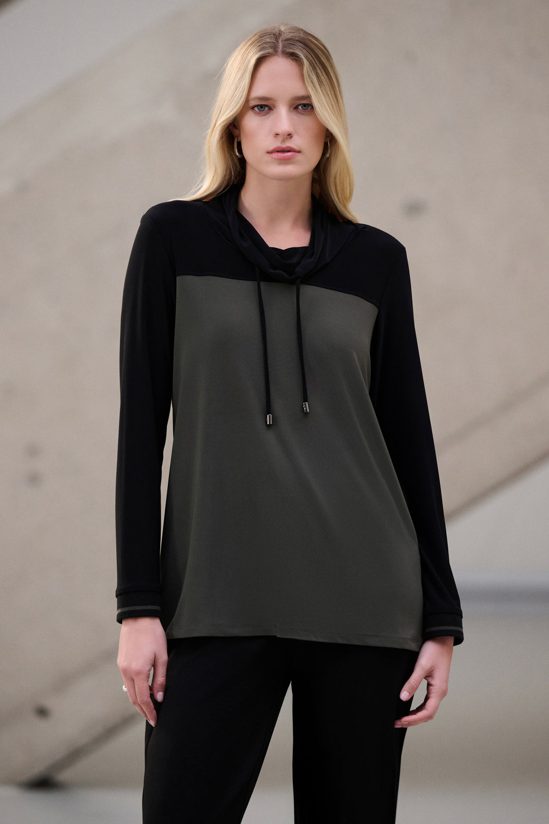 Woman wearing a black and gray long-sleeve cowl neck top against a neutral background