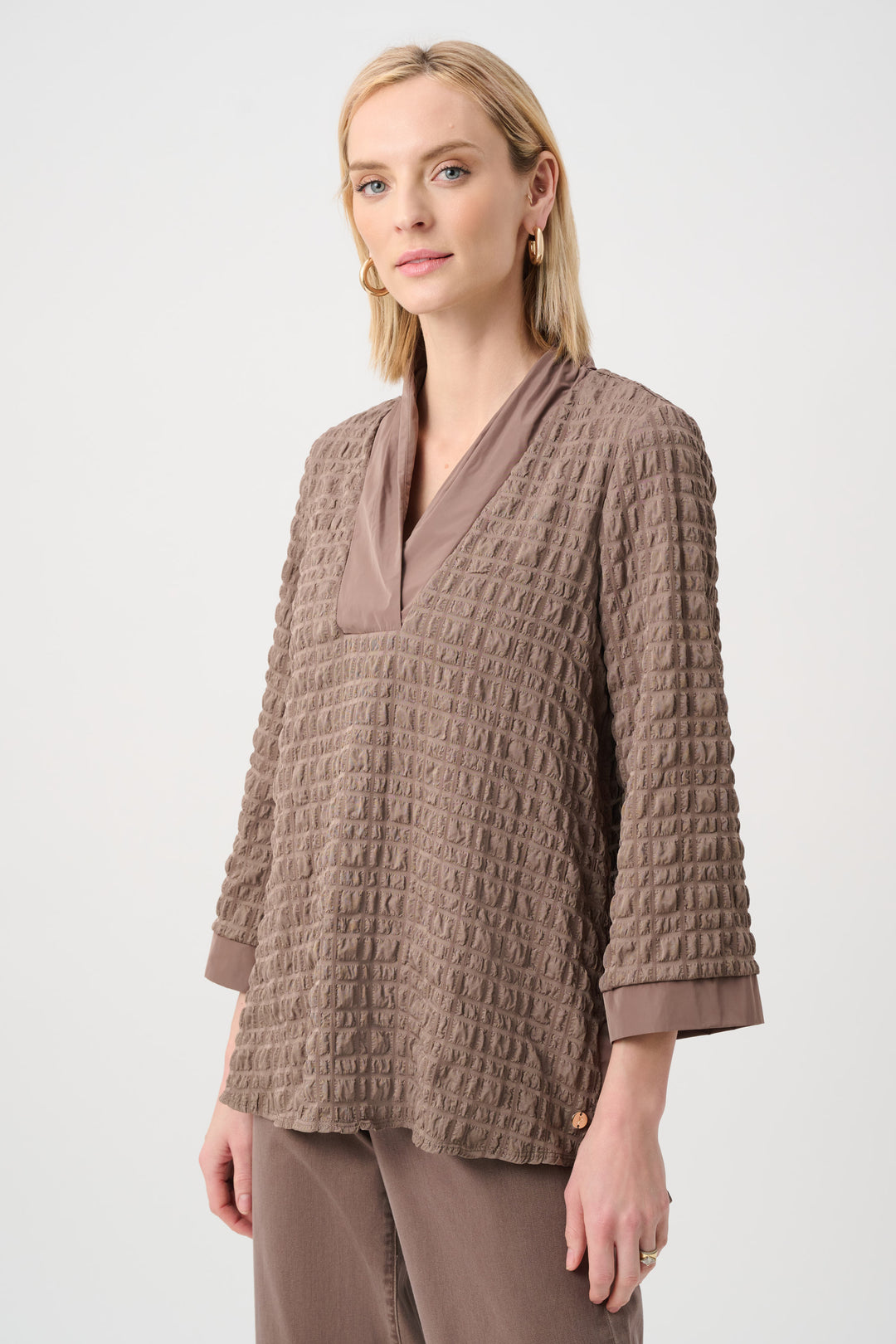 Woman wearing a textured brown light top with memory v-neck on a white background 