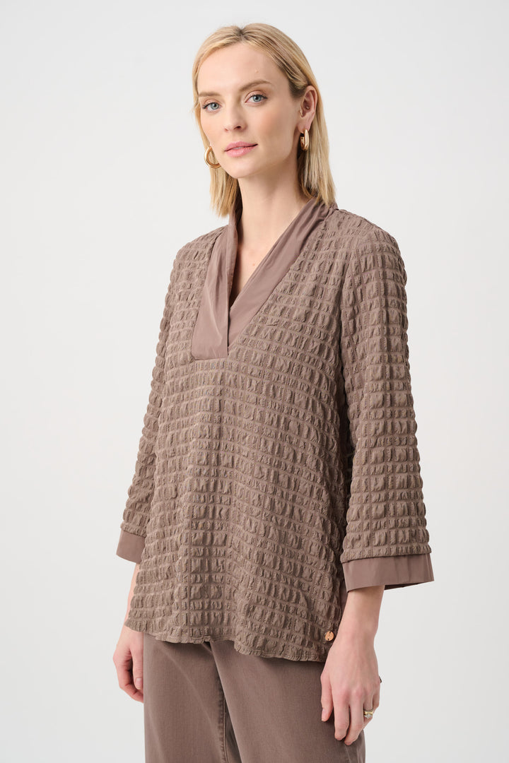 Woman wearing a textured brown light top with memory v-neck on a white background 