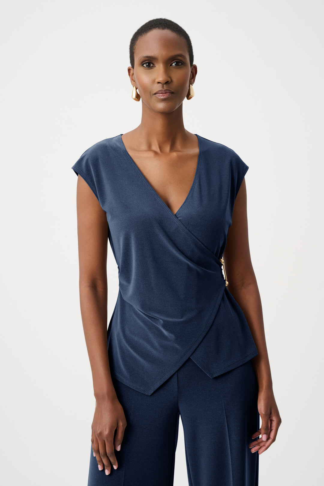 Woman wearing a blue wrap silky top with a draped front on a white background