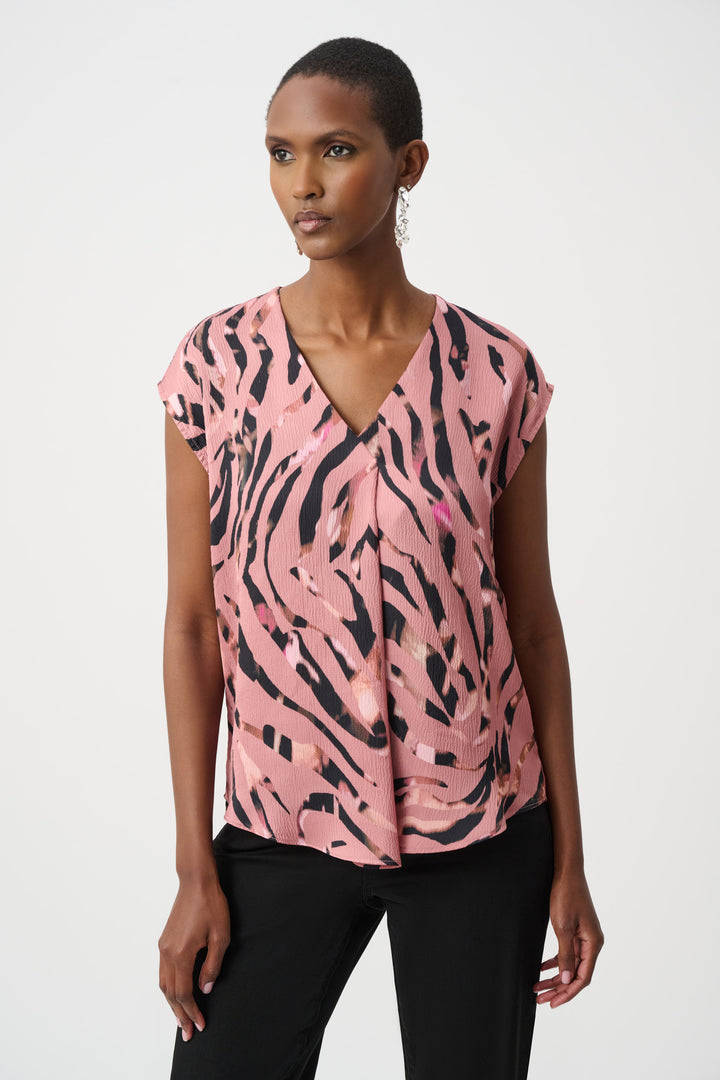 Woman wearing a pink and black patterned v-neck top against a white background