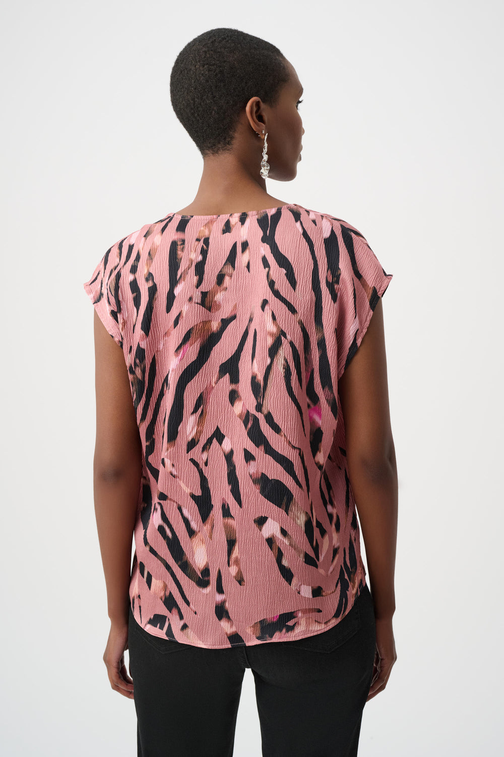 Woman wearing a pink and black patterned top on a white background