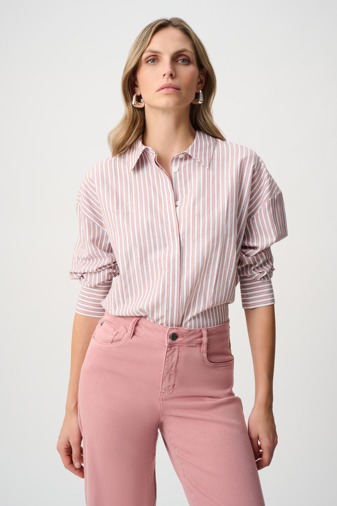 Woman wearing a striped shirt and pink pants against a white background