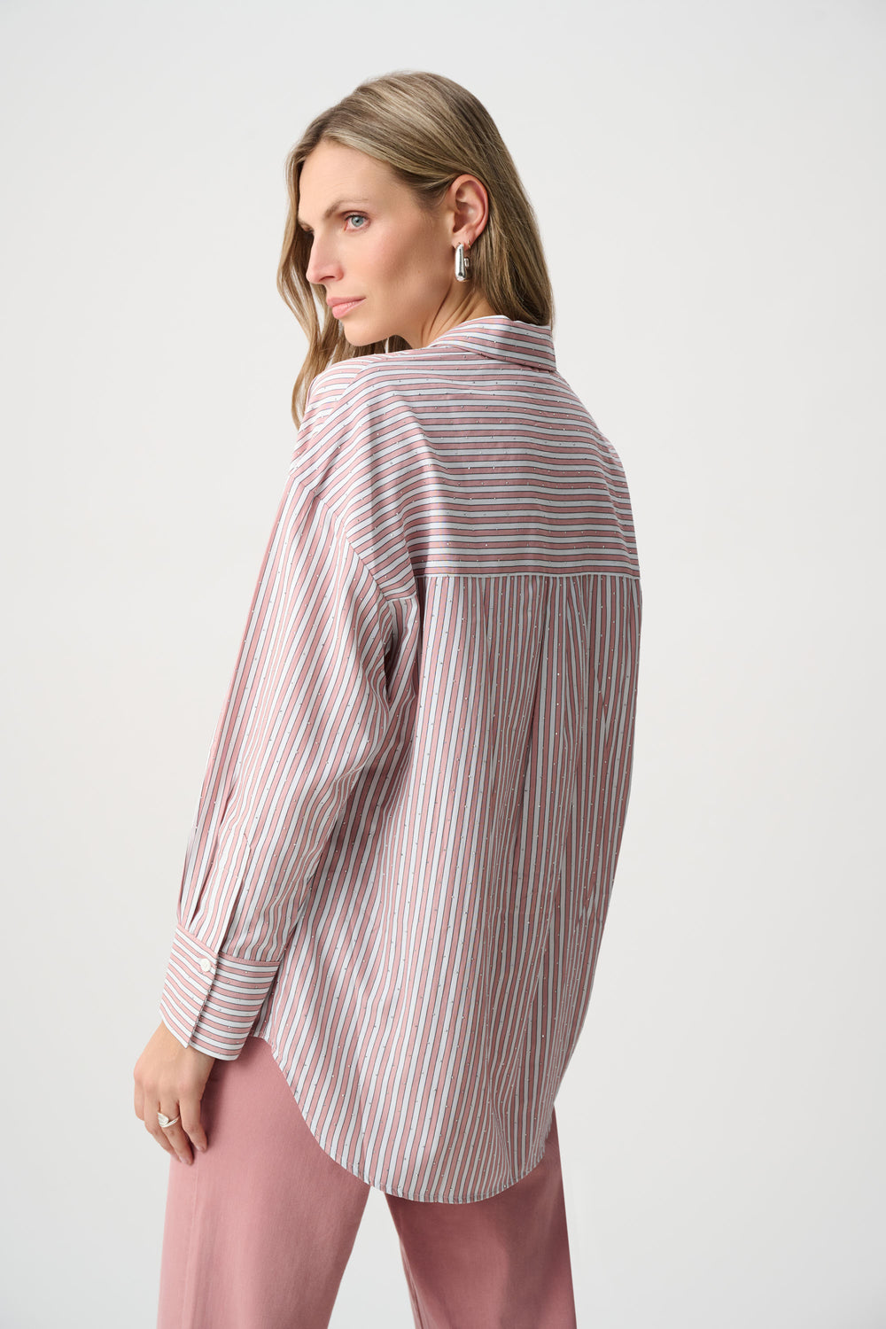 Woman wearing a striped shirt and pink pants on a white background