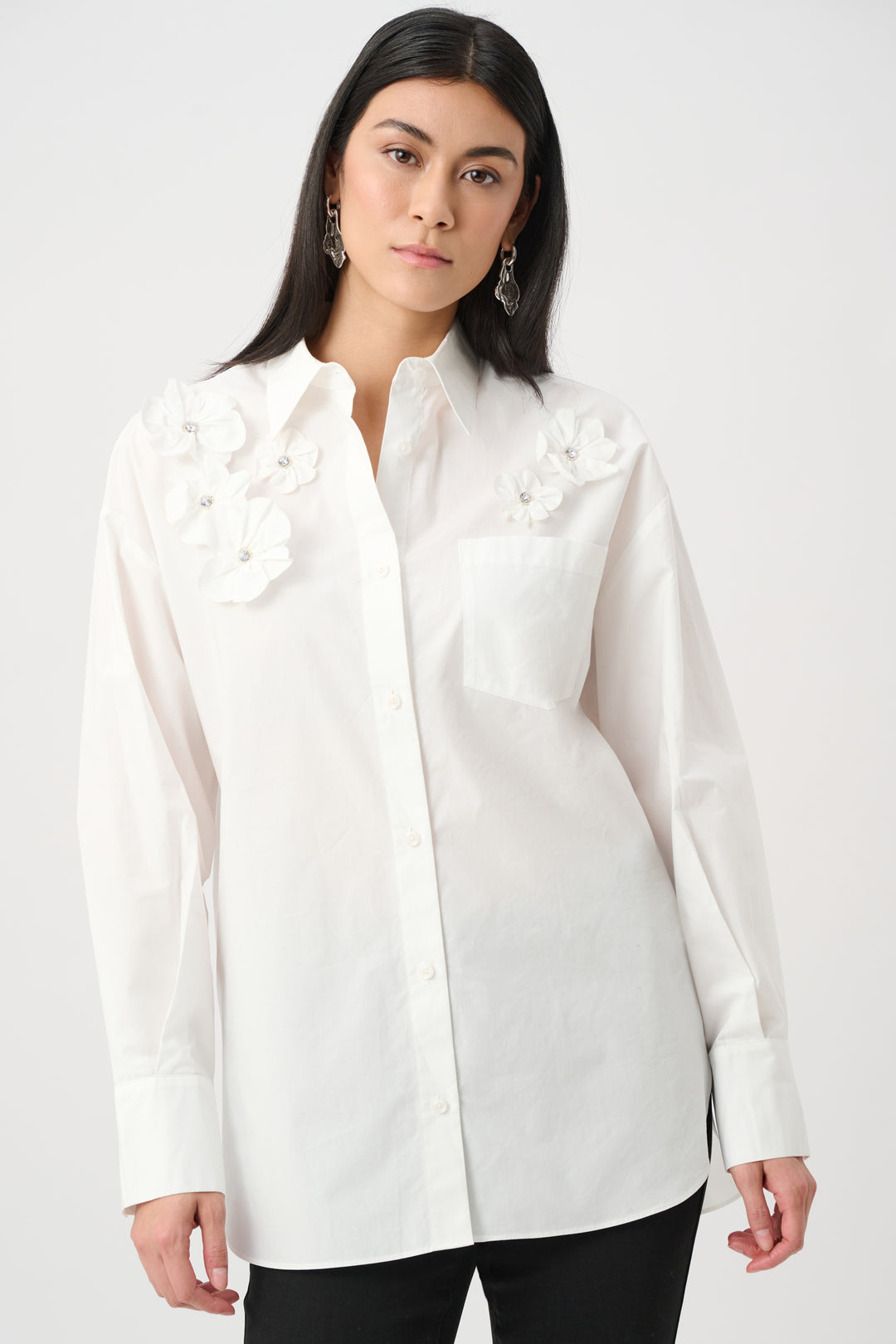 Woman wearing a white blouse with floral embellishments on a white background