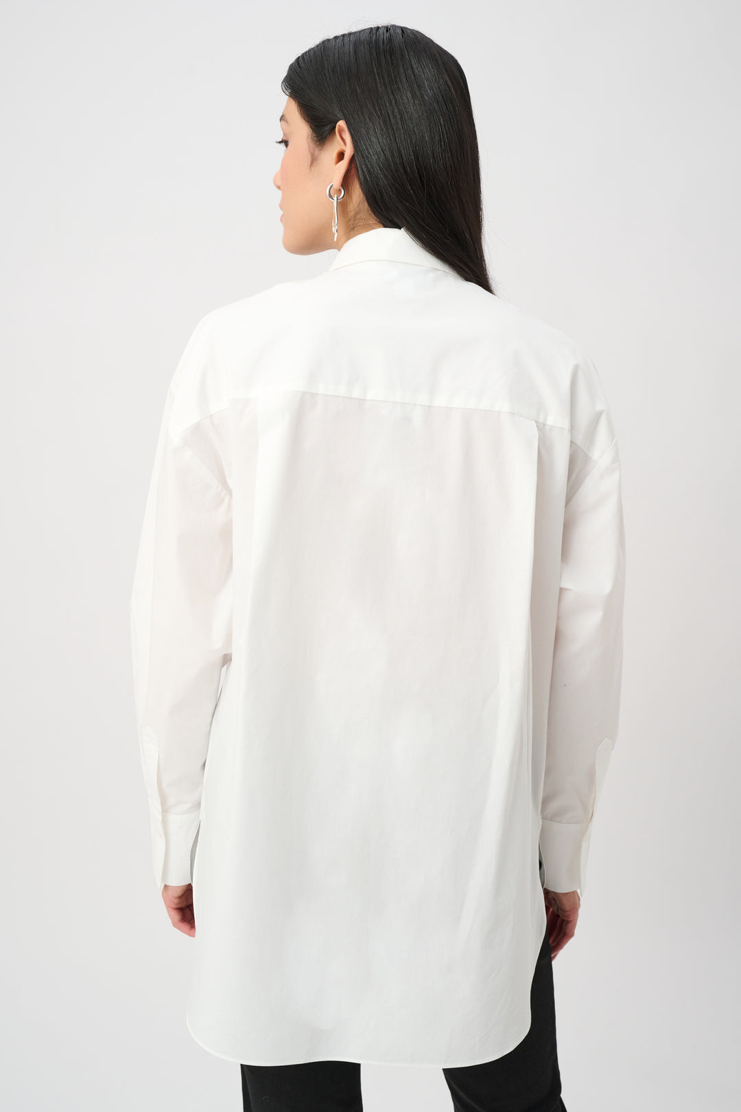 Person wearing a white long-sleeve shirt on a plain background