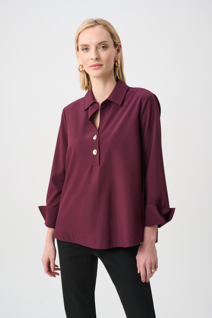 Woman wearing a burgundy blouse with a white background
