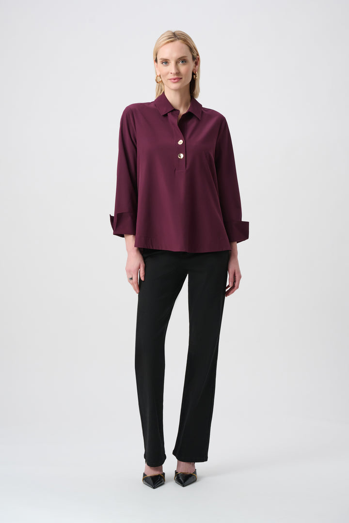 Woman wearing a burgundy blouse and black pants on a white background