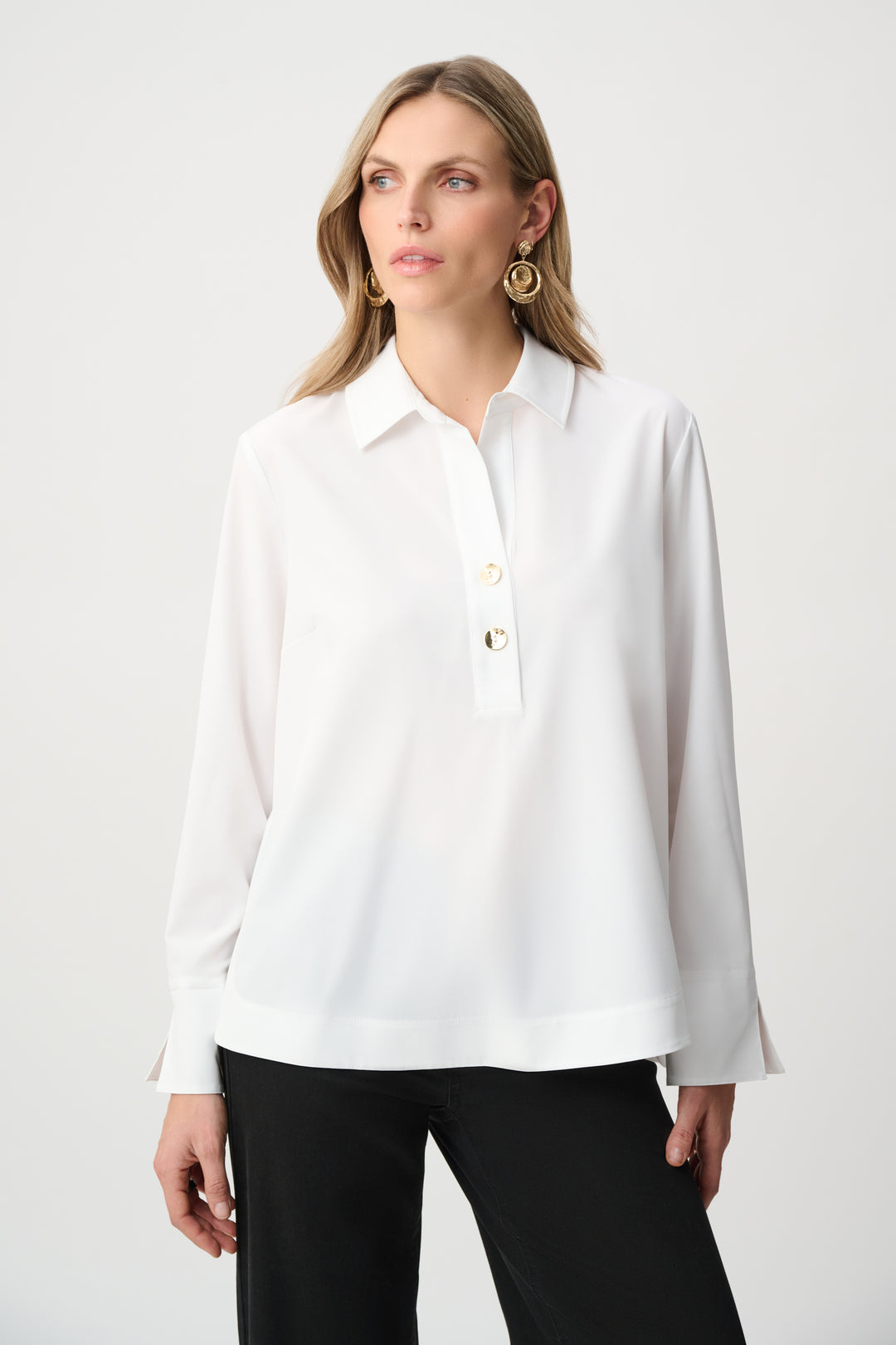 Woman wearing a white blouse with long sleeves on a plain background
