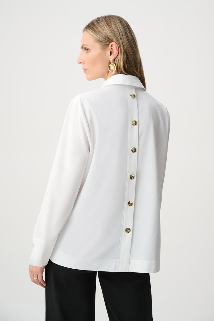 Woman wearing a white jacket with gold buttons on a plain background