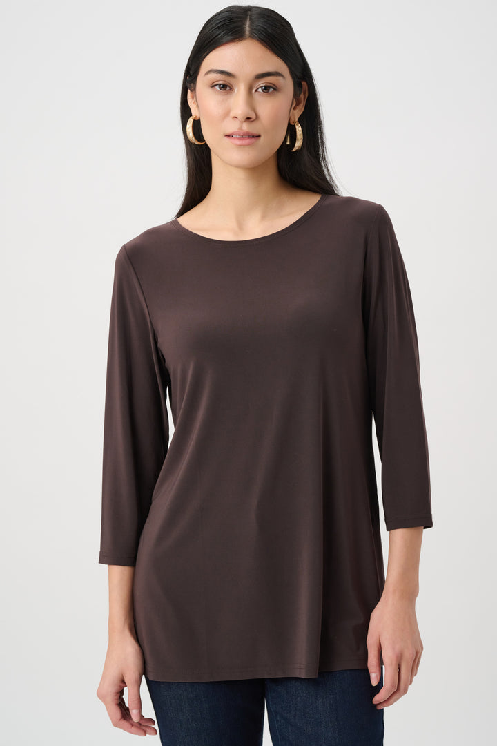 Woman wearing a brown long-sleeve top against a white background