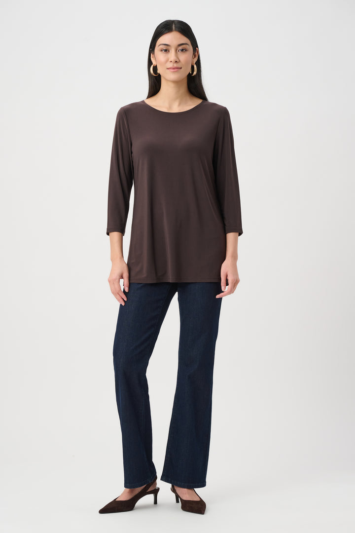 Woman wearing a brown long-sleeve top and dark blue pants on a white background